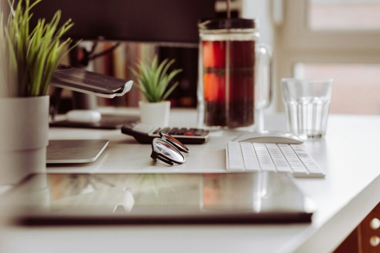 Home office with a laptop, monitors, filing cabinet, receipts, and an insurance policy on the desk